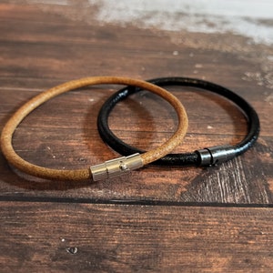 May include: Two leather bracelets, one brown and one black, with silver magnetic clasps.