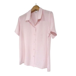 May include: A light pink short-sleeved button-down shirt with a collared neckline.