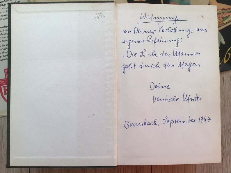 K&ouml;nnte beinhalten: Offenes Buch mit handschriftlichem deutschem Text in blauer Tinte. Der Text enth&auml;lt eine Widmung, ein Zitat und das Datum September 1964. Die Seiten des Buches sind cremefarben, und der Einband ist dunkelgr&uuml;n.