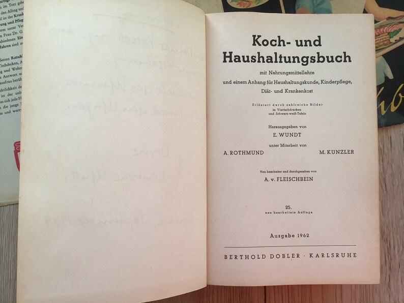 K&ouml;nnte beinhalten: Aufgeschlagenes Buch mit dem Titel "Koch- und Haushaltungsbuch" in deutscher Sprache. Der Einband zeigt schwarzen Text auf wei&szlig;em Hintergrund, einschlie&szlig;lich Titel, Untertitel und Autoreninformationen. Das Buch ist von 1962.