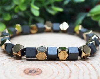 May include: A black and gold beaded bracelet with square and hexagonal beads.