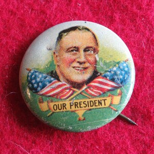 May include: A vintage button featuring a portrait of a man with the text "OUR PRESIDENT" and two crossed American flags.