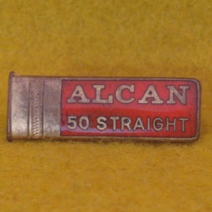 May include: A gold-colored metal box with a red label that says "ALCAN 50 STRAIGHT".