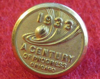 May include: A gold-colored button with the text "A Century of Progress Chicago 1933" and a stylized image of a globe and a comet.