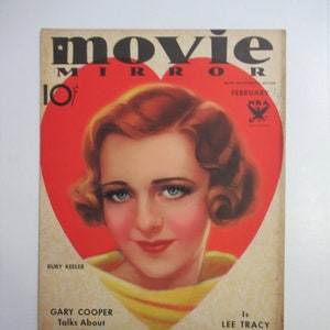 May include: Vintage "Movie Mirror" magazine cover featuring Ruby Keeler in a heart-shaped design. The cover has the text "February" and "Gary Cooper Talks About His Marriage". The magazine is in good condition with some wear.