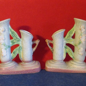 May include: A pair of vintage ceramic double bud vases with a green and white floral design. The vases are shaped like a tree trunk with two branches and have a light blue glaze.
