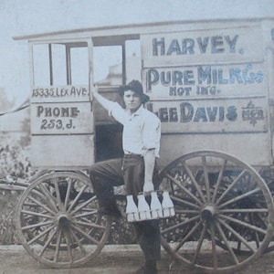 May include: A black and white photo of a horse-drawn wagon with a sign that reads 