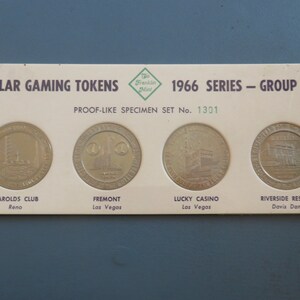 May include: A set of four silver dollar-sized gaming tokens in a white card holder. The tokens feature images of casinos and the text "1966 SERIES - GROUP 16" and "PROOF-LIKE SPECIMEN SET No. 1301".