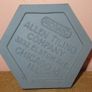 May include: A grey hexagonal tile with the text "Mosaic Allen Tiling Company 3232 Elston Ave. Chicago Ill."