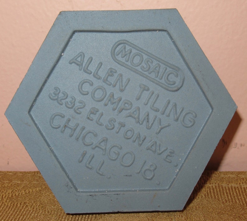 May include: A grey hexagonal tile with the text "Mosaic Allen Tiling Company 3232 Elston Ave. Chicago Ill."