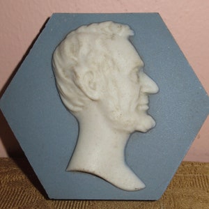May include: A white ceramic bust of Abraham Lincoln in profile, mounted on a blue hexagonal tile.