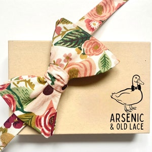 Papillon da uomo con motivo floreale color pesca, bordeaux, marrone e cipria della Rifle Paper Co., disponibile nella versione tradizionale da annodare o già annodato.