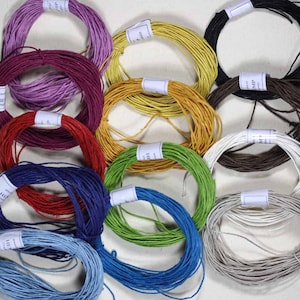 May include: Assortment of 12 spools of colourful paper twine. The twine is wound into circles and each spool has a white label with black text. The colours include purple, red, blue, green, yellow, brown, black, and white.