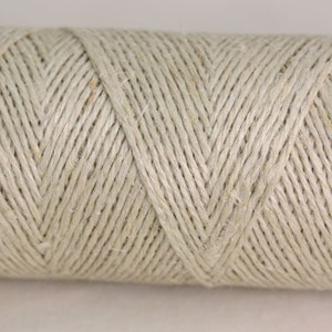 May include: A close-up of a spool of natural-colored twine. The twine is tightly wound and has a smooth, even texture.