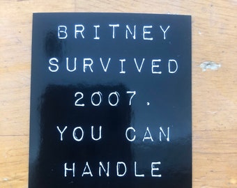 May include: Black and white sticker with the text "Britney Survived 2007. You Can Handle Today."