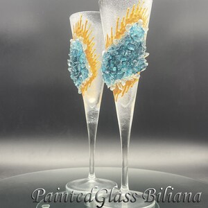 Peut inclure: Deux flûtes à champagne en verre transparent avec des motifs peints en or et bleu. Les motifs présentent un groupe de pièces de verre bleu avec des accents dorés.