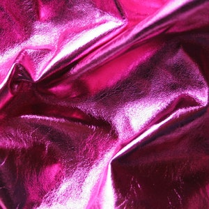 Peut inclure: Gros plan sur un tissu métallique rose vif avec une texture froissée. Le tissu a une surface brillante et réfléchissante.