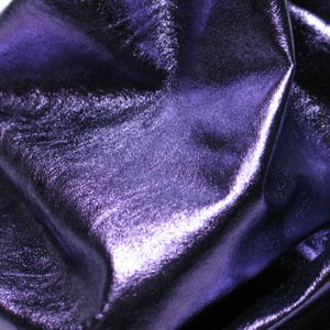 May include: Close-up of a piece of purple metallic leather with a smooth, shiny surface.