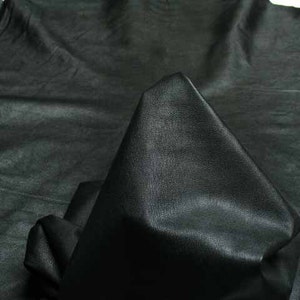 Puede incluir: Un trozo de cuero negro con una superficie lisa y texturizada. El cuero está doblado en forma de triángulo.