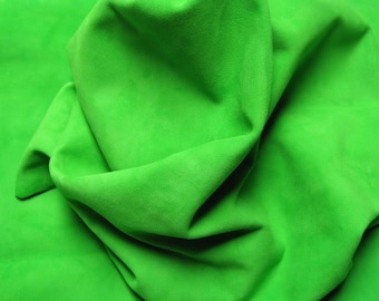 May include: A close-up of a bright green fabric with a soft, textured surface. The fabric is folded and draped, creating a smooth, flowing look.