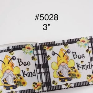 May include: A roll of 3-inch wide ribbon with a repeating pattern. The design features a gnome dressed as a bee, sunflowers, and the words "Bee Kind" on a white background with a black and white plaid border.