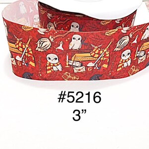 May include: A spool of red ribbon with a repeating pattern of owls, books, and other magical elements. The ribbon is 3 inches wide and features the text "#5216".