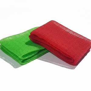 May include: Two mesh cloths, one folded in red and the other folded in green, are displayed on a white background. The cloths have a woven texture and are likely used for cleaning or washing. The image is well-lit, highlighting the vibrant colors and textures.