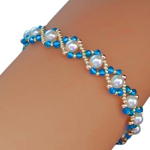 Peut inclure: Un bracelet de perles avec des groupes alternés de perles blanches et de perles bleues vives. Le bracelet est enfilé avec des perles dorées, créant un design délicat et élégant. Ce bijou est parfait pour ajouter une touche de sophistication.