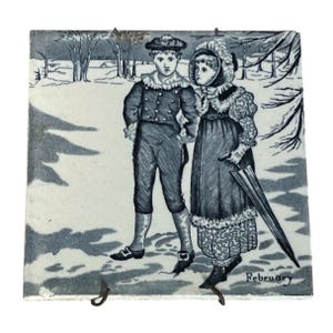 May include: A vintage blue and white tile depicting two children in winter clothing walking in the snow. The tile has the word "February" printed at the bottom.