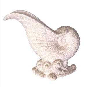Puede incluir: Un jarrón de cerámica de color crema con forma de concha de nautilo y una superficie texturizada y granulada. El recipiente presenta una abertura ancha y curva en la parte superior y una base decorada con patrones ondulados y en espiral.