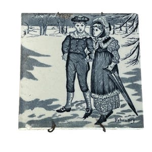 May include: A square ceramic tile featuring a black and white illustration of two figures in winter attire walking through a snowy landscape. The person on the left wears a cap and suit, while the person on the right wears a bonnet and coat, holding an umbrella. The word February is printed in the bottom right corner.