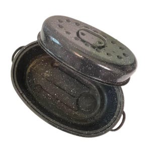May include: Black oval roasting pan with a speckled white pattern. The pan has a matching lid with a handle and air vents. The pan has two side handles for easy carrying. The pan is made of metal.