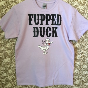 May include: A lavender t-shirt with the text "FUPPED DUCK" in black lettering. A cartoon duck with red eyes is smoking a cigarette.