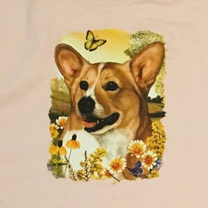 K&ouml;nnte beinhalten: Ein brauner und wei&szlig;er Corgi-Hund mit einem gelben Schmetterling &uuml;ber seinem Kopf. Der Hund ist von gelben und wei&szlig;en Blumen und einem blauen Schmetterling umgeben.