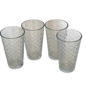 Puede incluir: Cuatro vasos transparentes con un patrón texturizado de puntos. Los vasos son altos y cilíndricos, adecuados para agua, zumos u otras bebidas. Los vasos son de vidrio transparente y están sobre un fondo blanco.