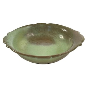 May include: A ceramic bowl with a scalloped edge. The bowl features a gradient of colours, with a light green interior and a darker, brownish-green exterior. The rim has a slightly raised edge.