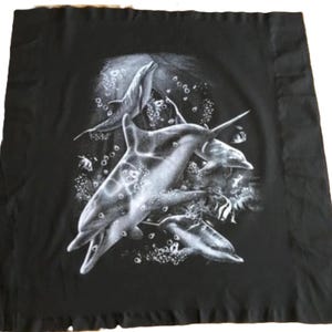 Puede incluir: Tela negra con un estampado gráfico blanco de tres delfines nadando en un banco de peces. Los delfines están en varias poses, uno saltando fuera del agua. El fondo es azul oscuro, y hay burbujas y algas en el agua.