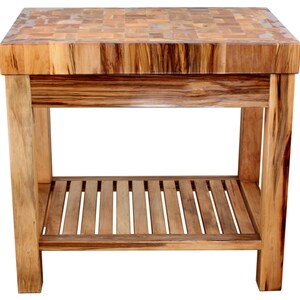 May include: A wooden butcher block kitchen island with a butcher block top and a lower shelf. The island is made of light brown wood with a natural finish.