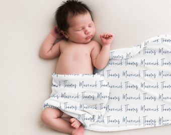 Może przedstawiać: Noworodek śpi na białym kocu z powtarzającymi się imionami "Maverick Thomas" napisanymi niebieskim pismem.
