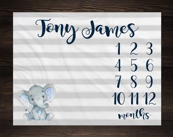 May include: A white and gray striped baby milestone blanket with a blue and gray elephant illustration. The blanket has the name "Tony James" and numbers 1 through 12 to track a baby's growth in months.