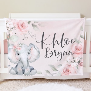 May include: Pink baby blanket with a floral design and a gray elephant with a pink flower crown. The blanket has the name "Khloe Brynn" written in black cursive.