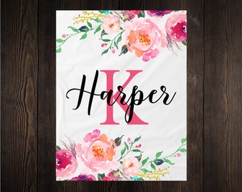 May include: A white personalized blanket with a pink floral design and the name "Harper" with a pink letter K.
