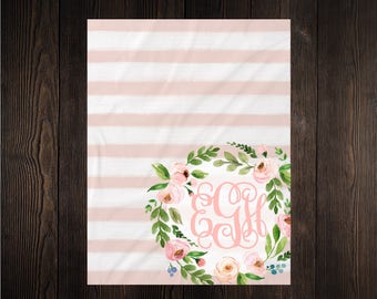 May include: A pink and white striped baby blanket with a floral wreath and the monogram "CGH" in pink.