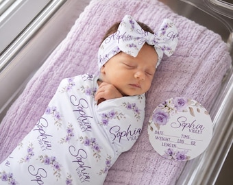 May include: A white swaddle blanket and matching headband featuring a purple floral pattern and the name Sophia Violet printed in black script. A circular white sign with matching floral graphics and the name Sophia Violet with blank lines.
