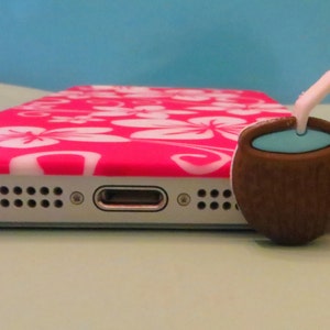 May include: A pink and white floral phone case with a brown coconut-shaped phone charm with a blue liquid inside and a white straw.