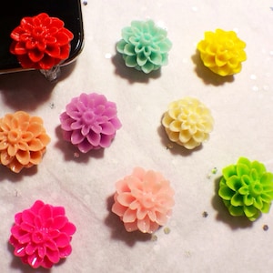 May include: Assortment of eight colorful flower-shaped phone charms. The charms are made of resin and feature a variety of colors, including red, pink, purple, yellow, green, and white.