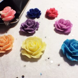 May include: A collection of colorful, resin rose embellishments in various shades, including pink, blue, purple, orange, and yellow. These decorative flowers are ideal for crafting projects or adding a floral touch to accessories.
