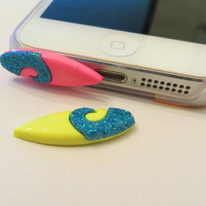 May include: Two small, colorful surfboard-shaped phone charms with blue glitter waves. The charms are made of plastic and have a glossy finish.