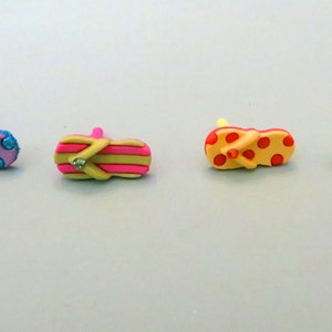 May include: Four colorful flip-flop charms with different designs, including polka dots, stripes, and a single rhinestone.