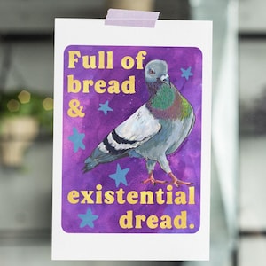 Puede incluir: Impresión rectangular blanca con fondo morado y dibujo de paloma. El texto "Full of bread & existential dread" está en dorado y azul. La impresión está pegada a una superficie de vidrio con cinta adhesiva.